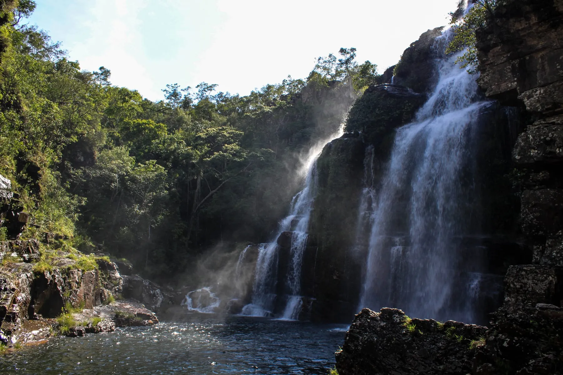 Cachoeira das Almécegas: queda alta e estreita despencando de um paredão escuro cercado de mata