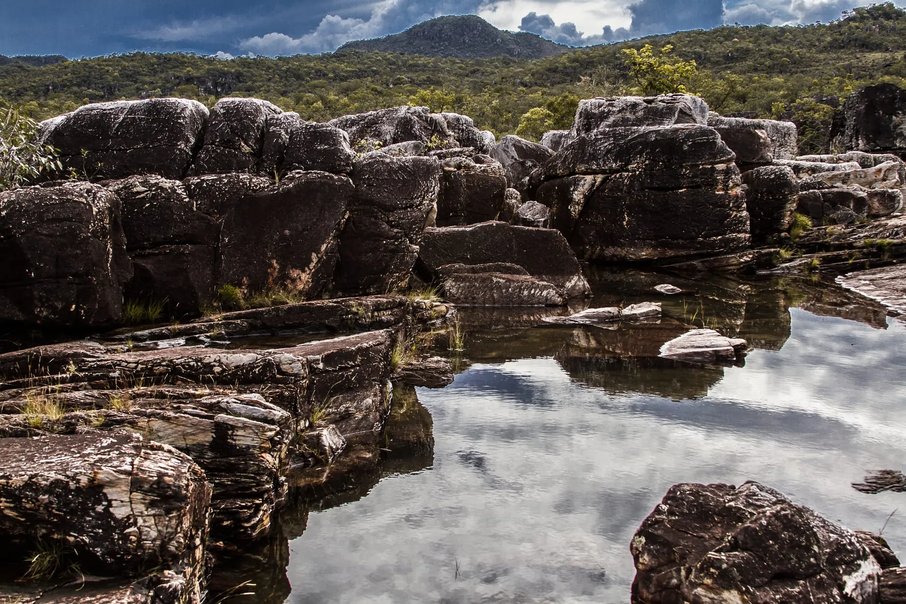 Rio correndo entre paredes de rocha escura no cânion, com vegetação de Cerrado nas margens