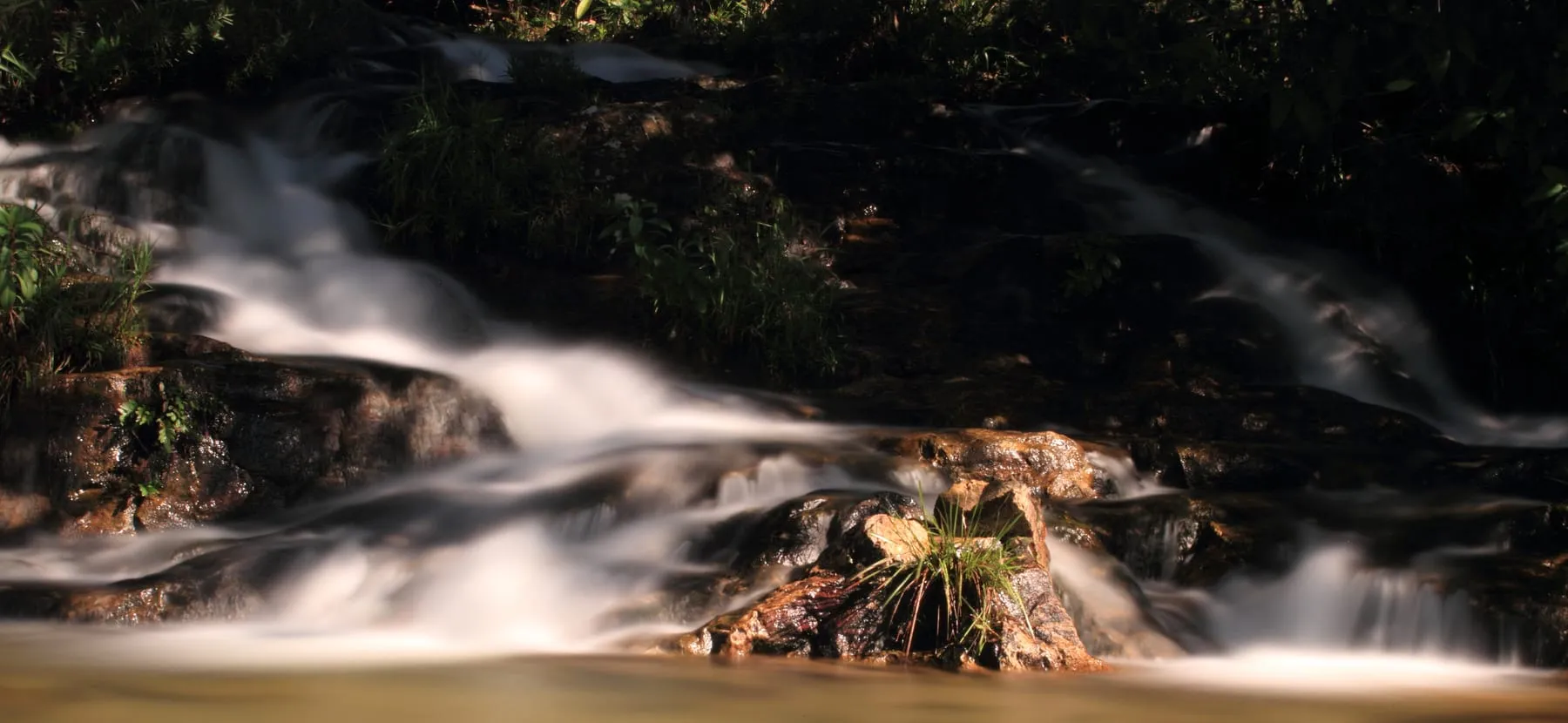 Cachoeira dos Cristais em longa exposição, a água descendo como véu sobre degraus de rocha