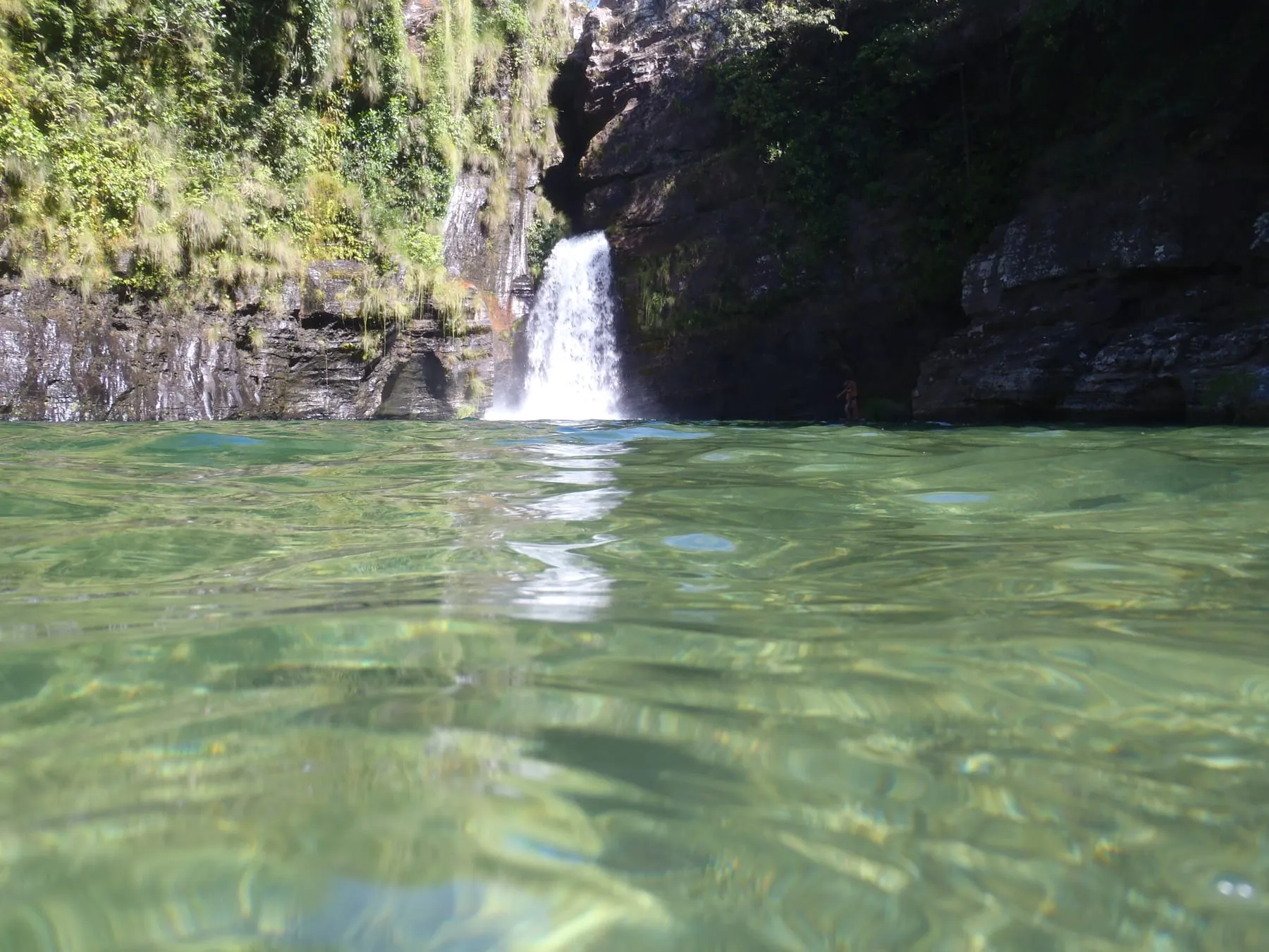 Cachoeira do Prata caindo num poço de água esverdeada e transparente, cercada de mata fechada