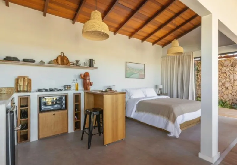 Cozinha equipada ao lado da cama, com luminárias de palha e teto de madeira