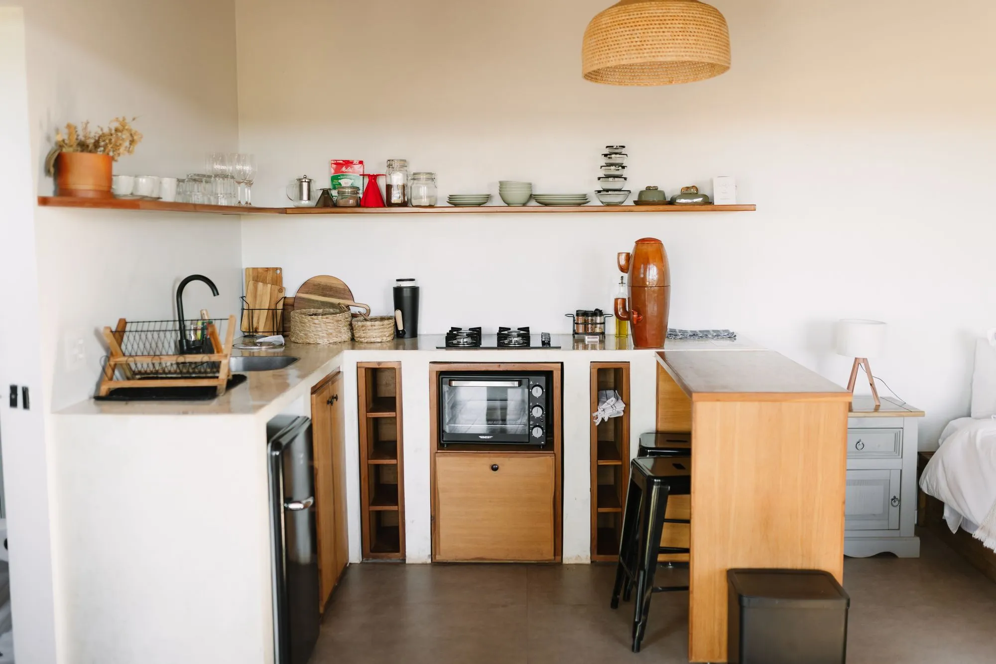 Cozinha com frigobar retrô preto, forno elétrico, cooktop, prateleiras de louça e bancada de madeira