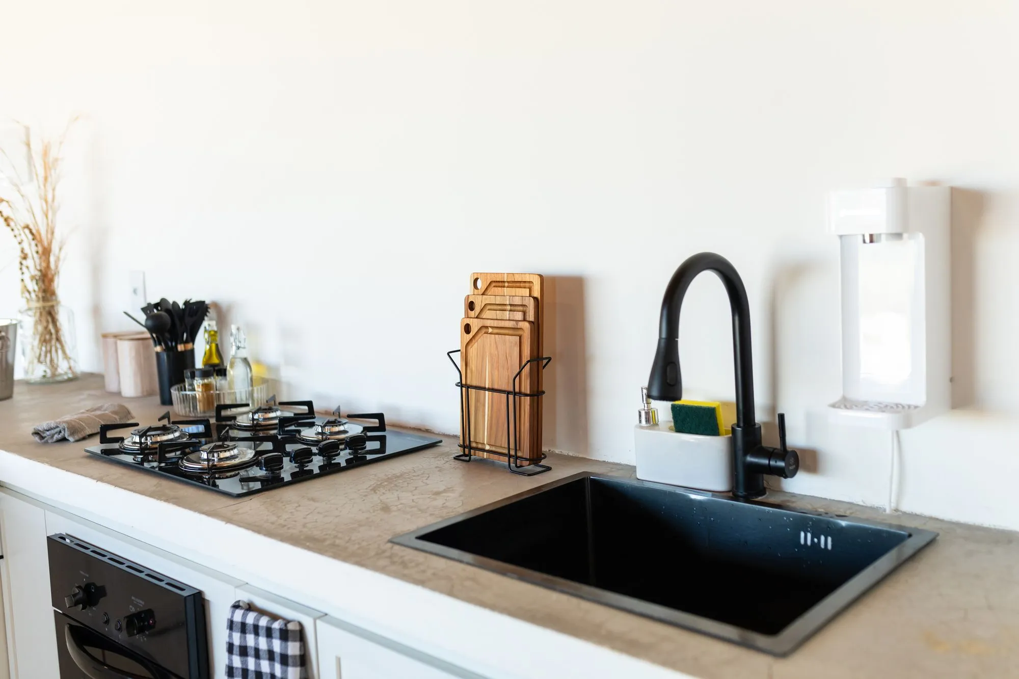Cooktop de quatro bocas, pia preta e tábuas de corte na bancada