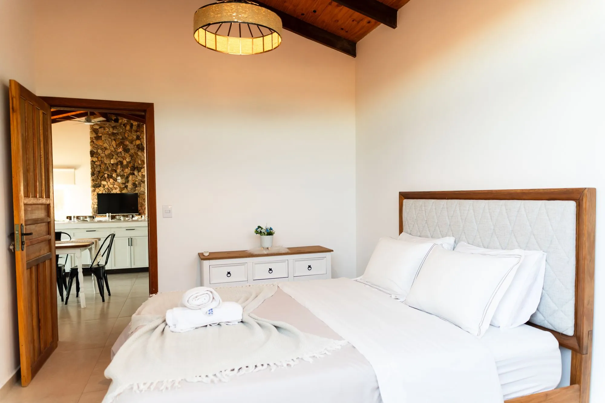 Primeiro quarto com a porta de madeira aberta para a sala e a cozinha