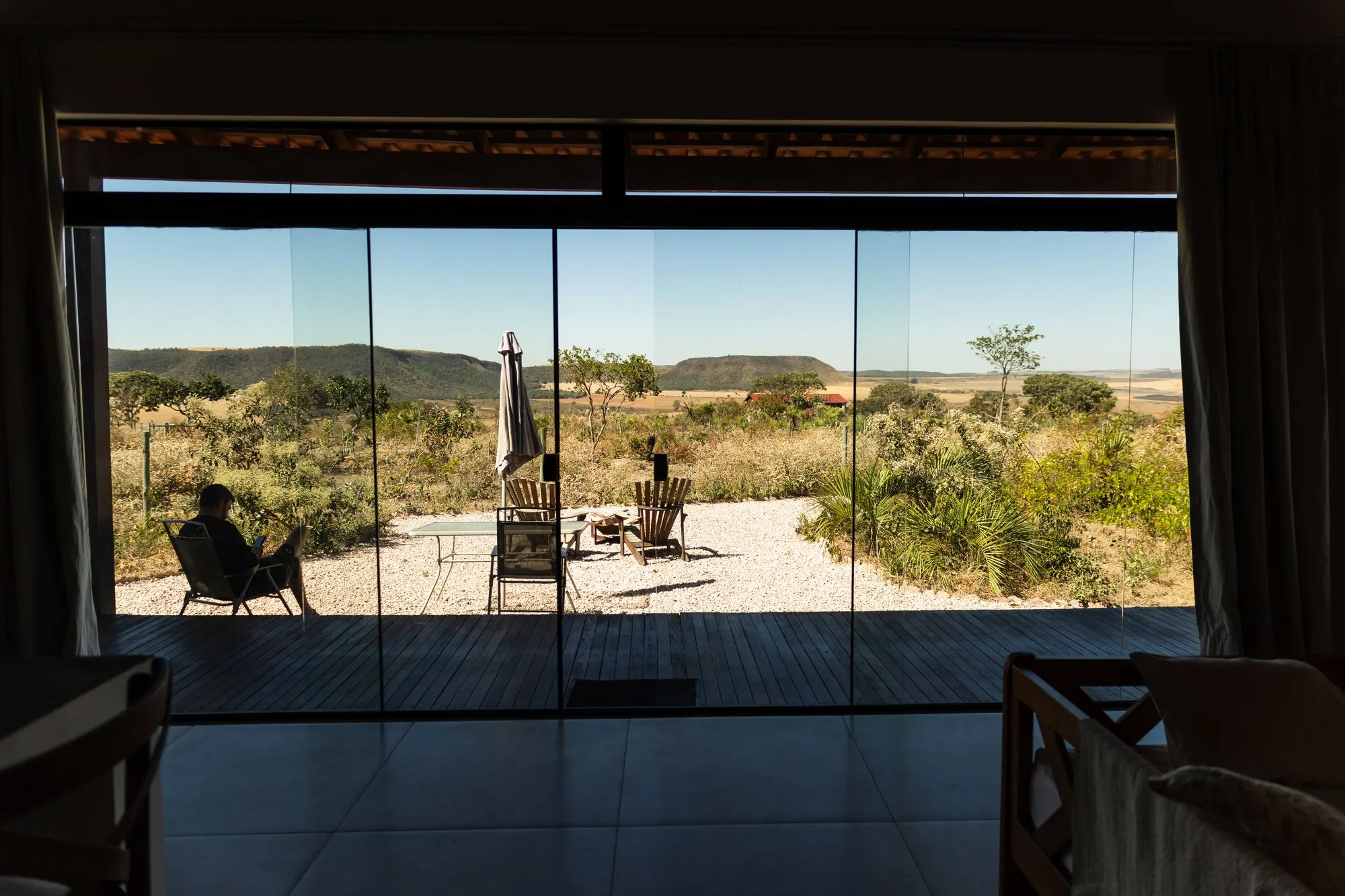 Da sala, a porta de vidro abre para o pátio e para a vista das chapadas
