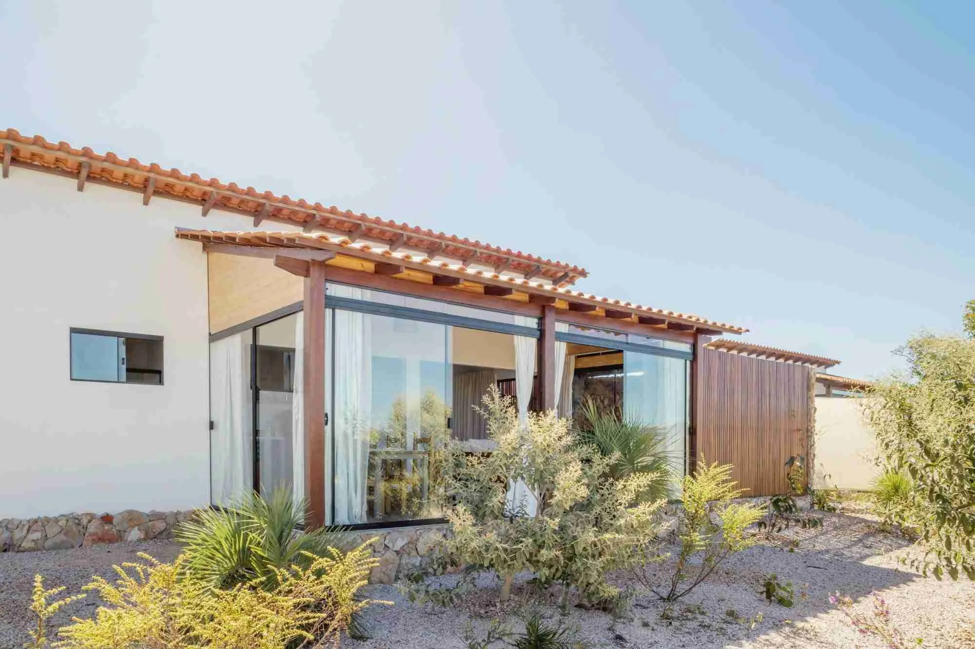 Chalet facade with large glass doors, a wooden frame and a garden of native Cerrado plants