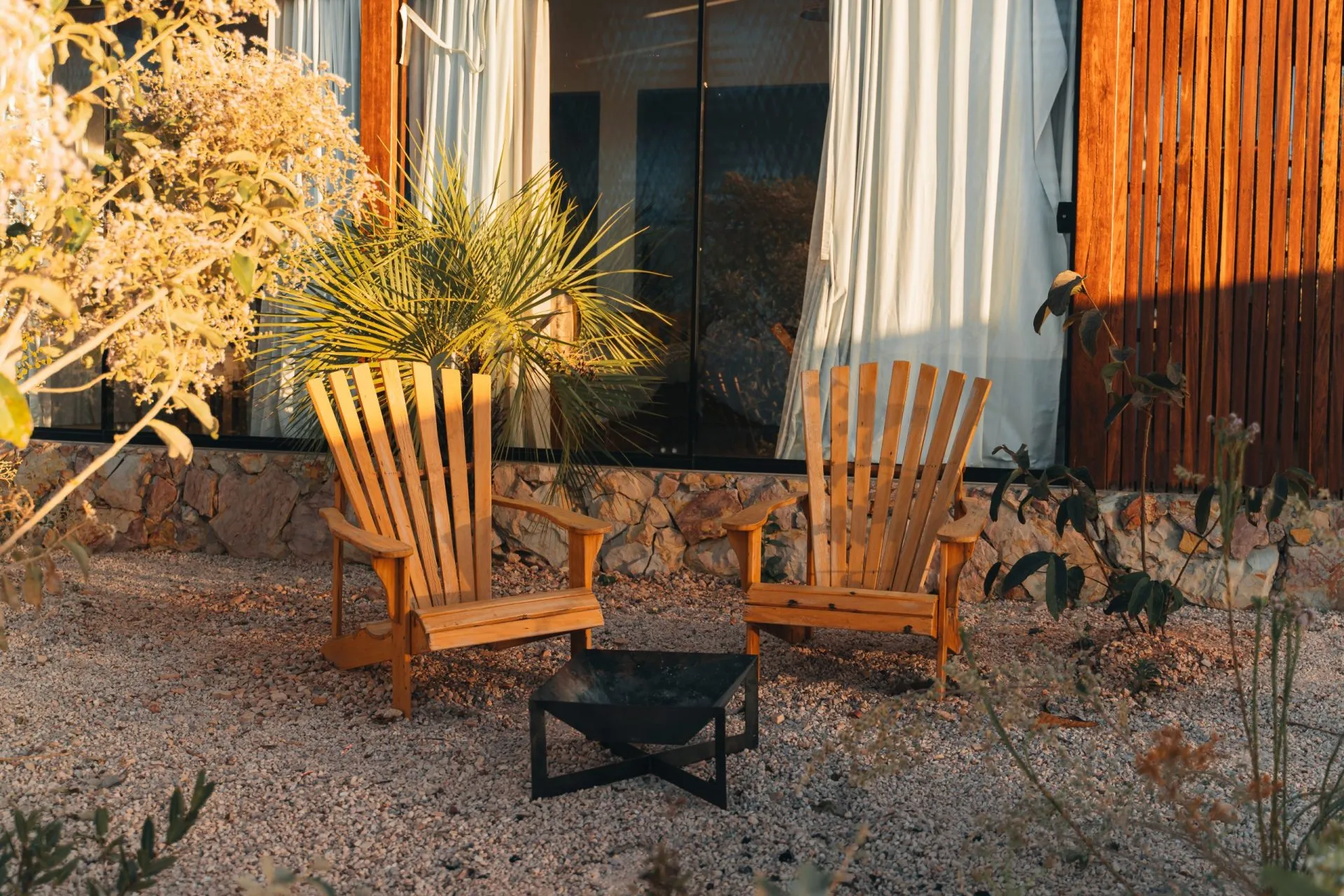 Chalet outdoor area with two wooden Adirondack chairs and a ground fire pit at dusk