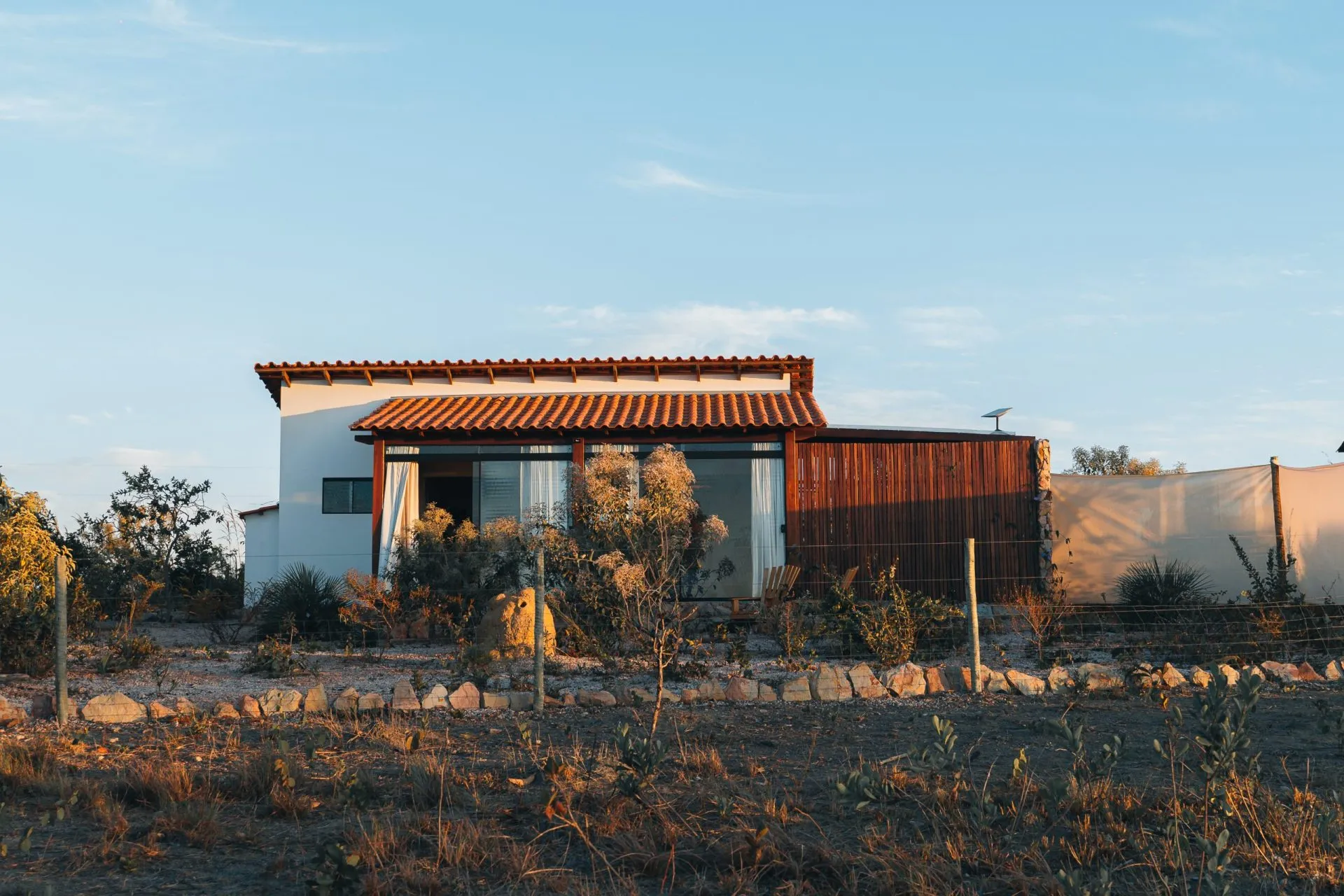 Chalet at sunset with golden light on the facade and dry Cerrado vegetation