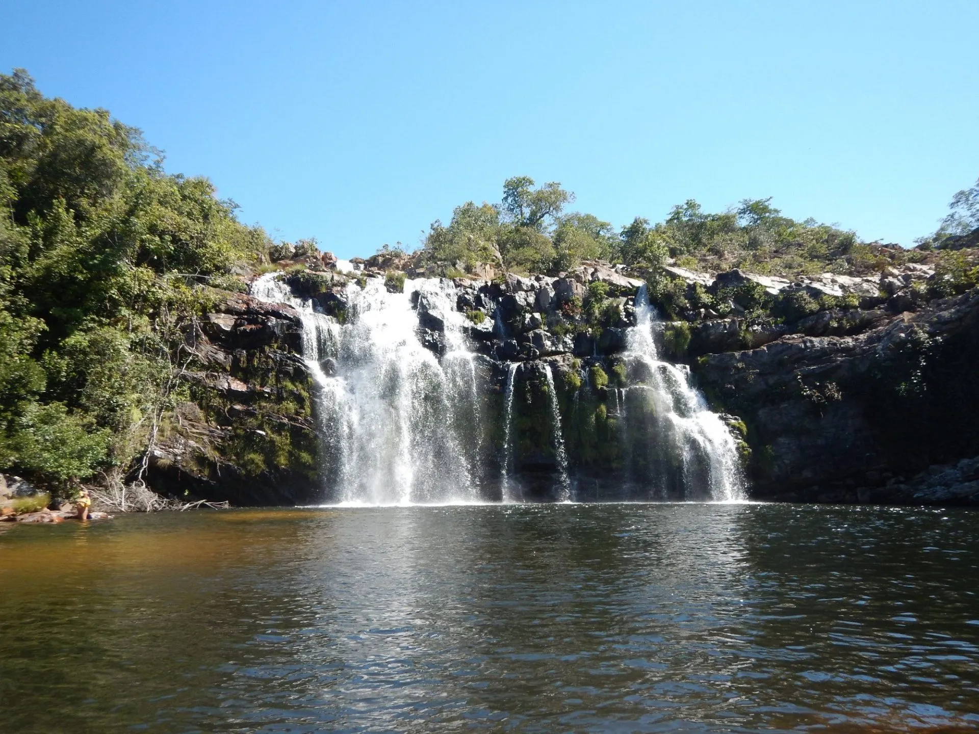 Cachoeira do Poço Encantado com múltiplas quedas d'água sobre rochas e poço natural para banho